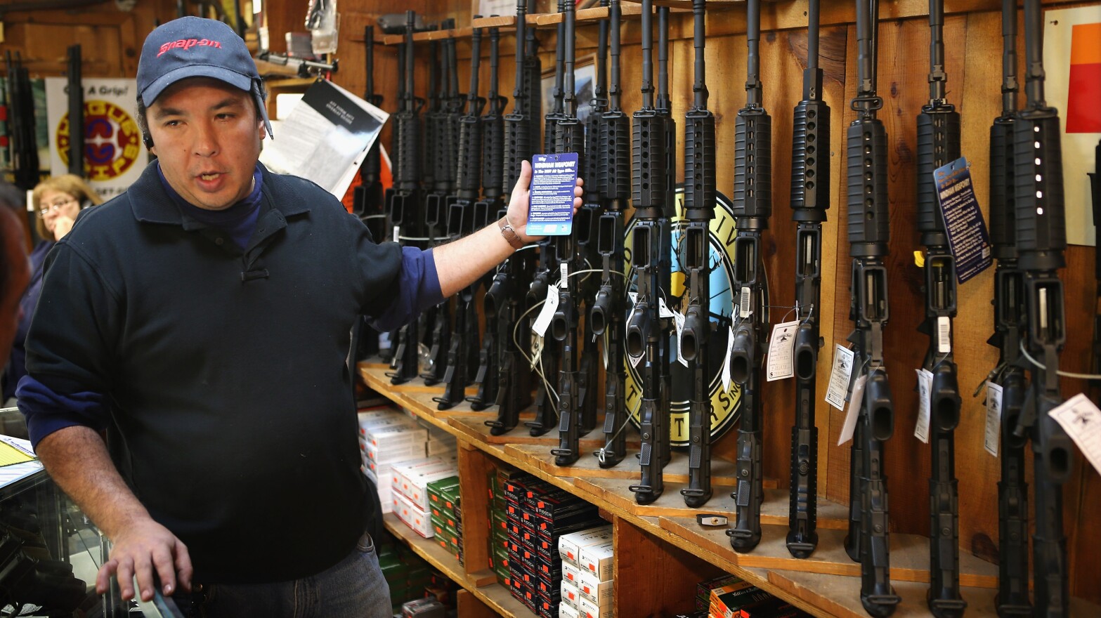 At the Freddie Bear Sports shop in Tinley Park, Ill., Jason Zielinski shows AR-15 style rifles to a customer.
